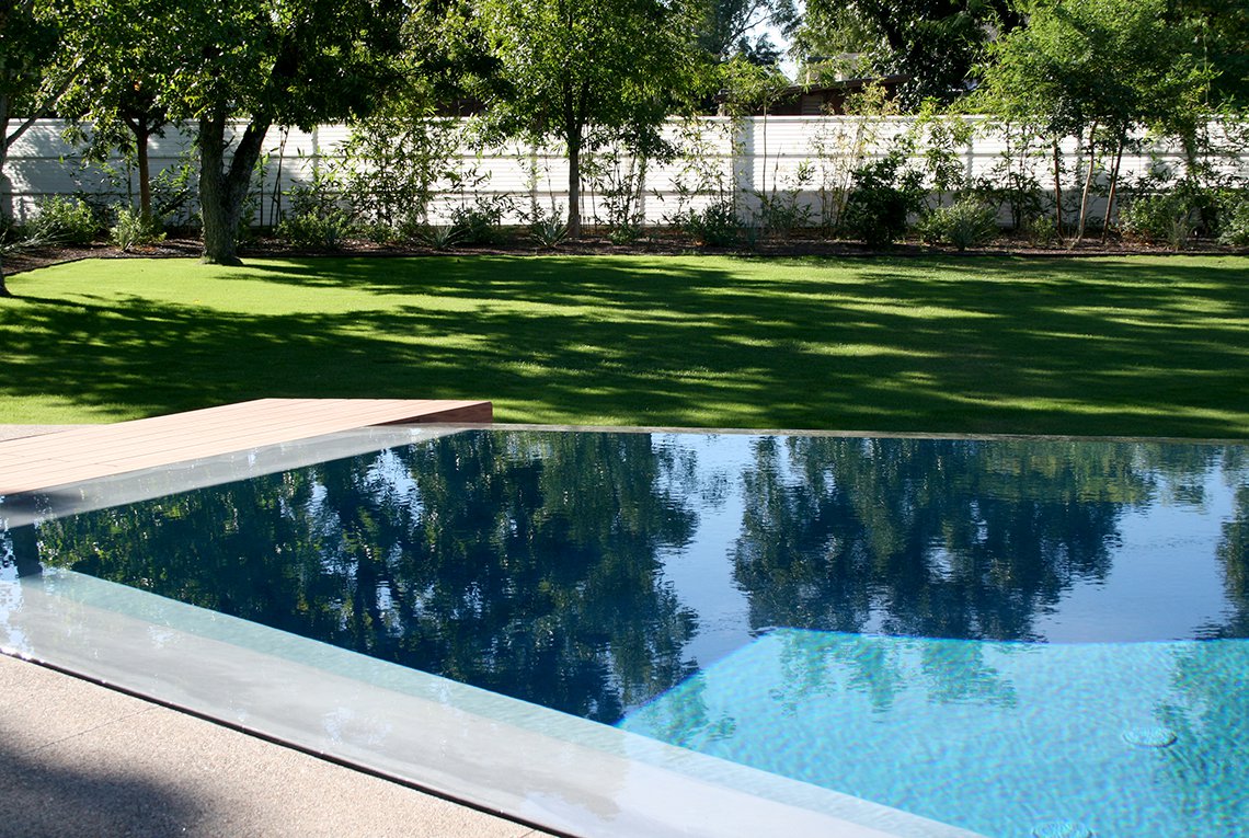 Modern, contemporary backyard custom landscape architecture design by On Site Landscape in Arcadia, Arizona, featuring a negative edge pool with cool plank decking details for a crisp visual aesthetic at this luxury property.